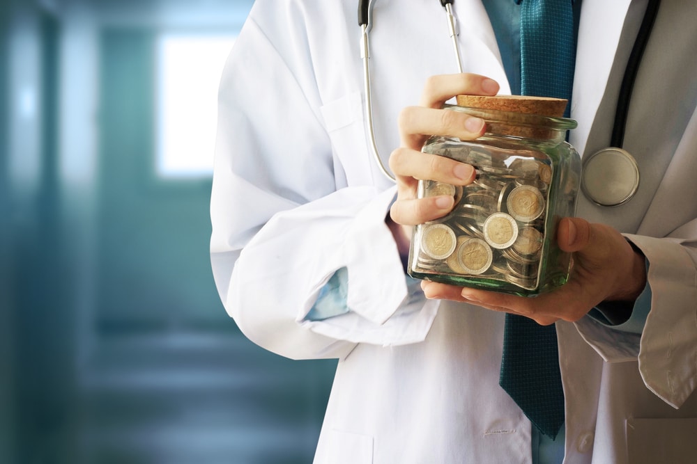 A pharmacist holds a jar of coins.