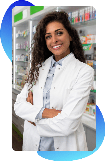 A pharmacist in a lab coat smiles at the camera with her arms crossed.