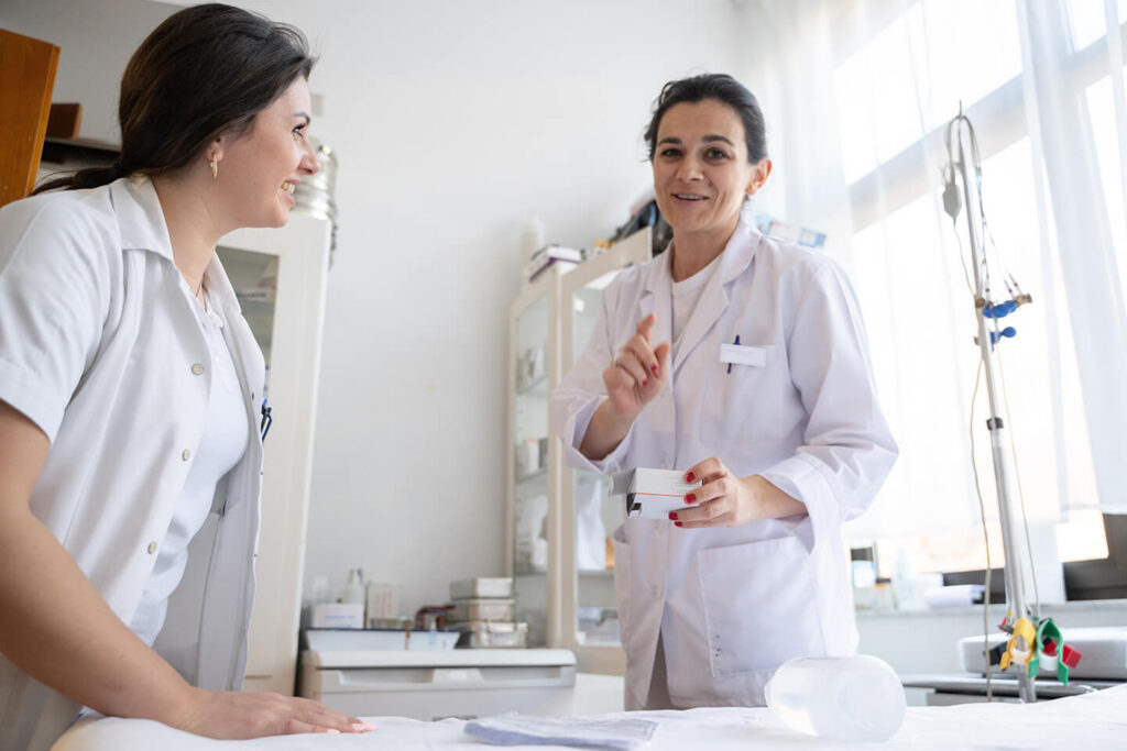 Two medical professionals in lab coats discussing treatment details in a bright clinical setting.